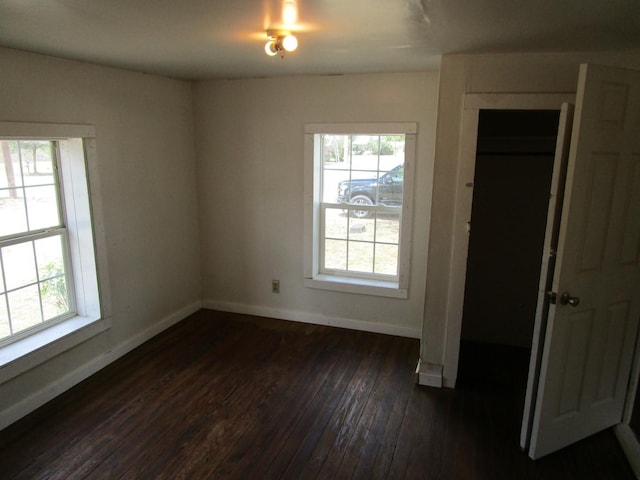 spare room with dark wood-type flooring and plenty of natural light