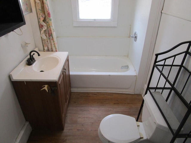 bathroom featuring hardwood / wood-style floors, toilet, vanity, and a bathing tub