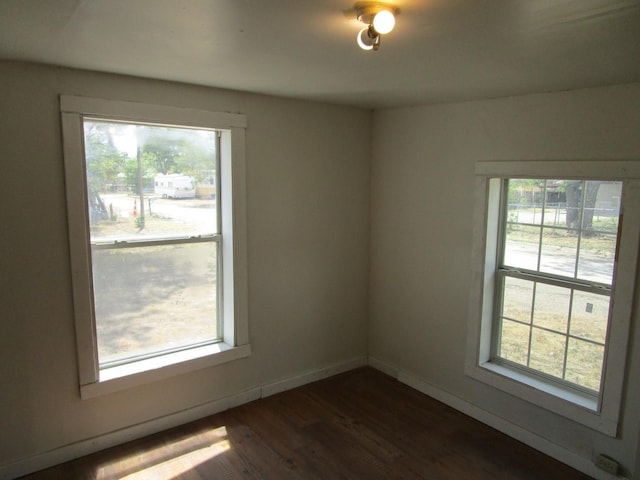 spare room with a wealth of natural light and dark hardwood / wood-style floors