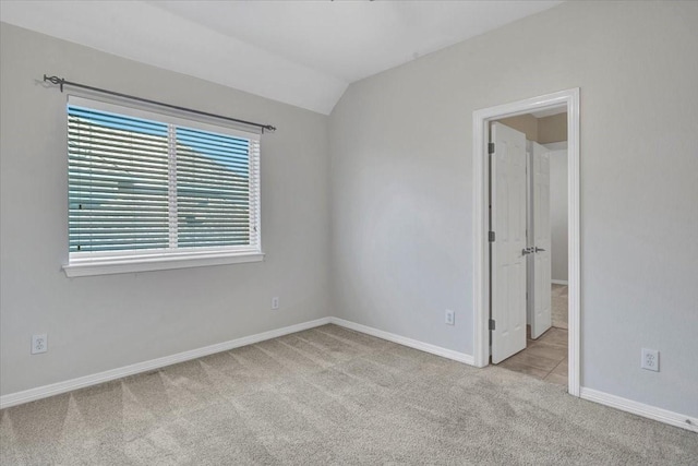 spare room with vaulted ceiling and light colored carpet