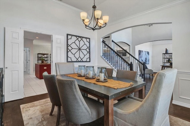 dining space featuring hardwood / wood-style flooring, crown molding, and an inviting chandelier