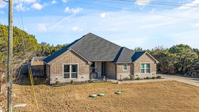 view of front of house with fence, brick siding, stone siding, and a shingled roof