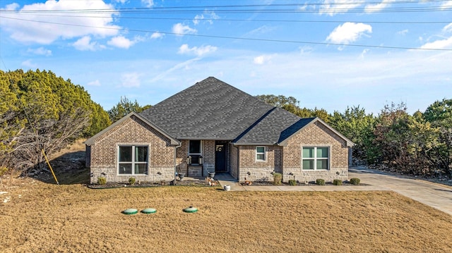 view of front of house with a front yard, stone siding, brick siding, and roof with shingles