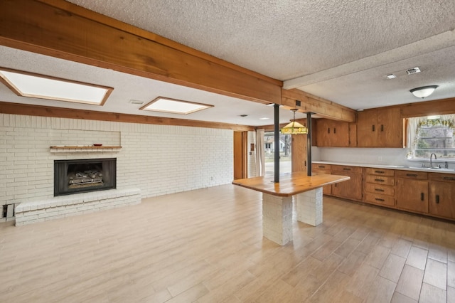 kitchen featuring brick wall, sink, hanging light fixtures, and a wealth of natural light