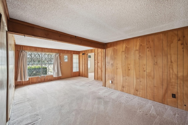 carpeted empty room with a textured ceiling and wood walls