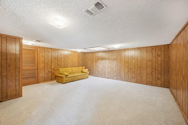 interior space with a textured ceiling, light colored carpet, and wooden walls