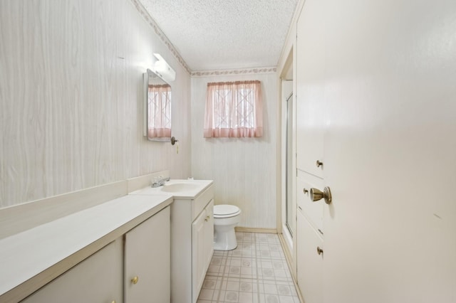 bathroom featuring a textured ceiling, toilet, vanity, and an enclosed shower