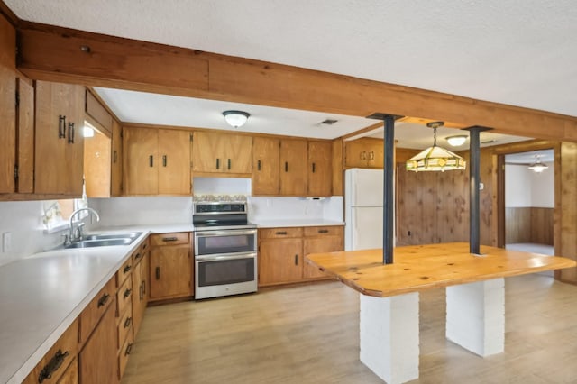 kitchen with decorative light fixtures, white fridge, double oven range, sink, and light wood-type flooring