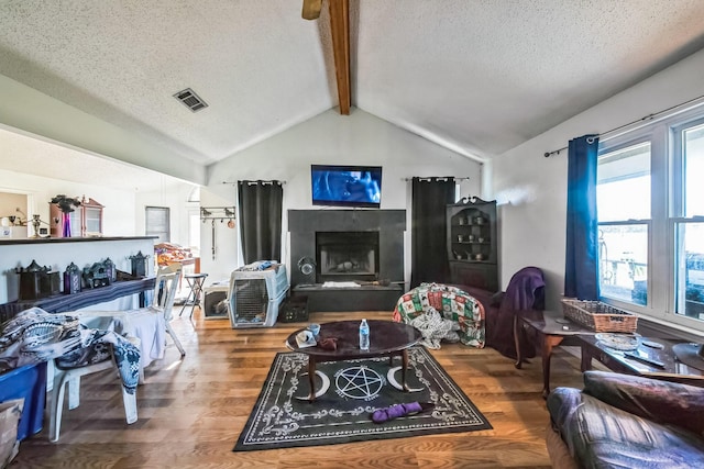 living room featuring a textured ceiling, lofted ceiling with beams, and hardwood / wood-style floors