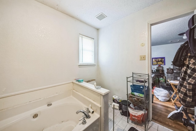 bathroom with a textured ceiling, tile patterned flooring, and a bath