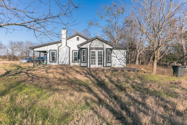 rear view of property with a lawn and french doors