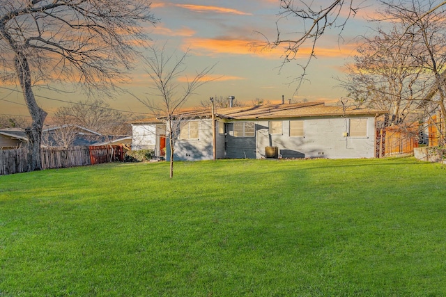 back house at dusk featuring a lawn