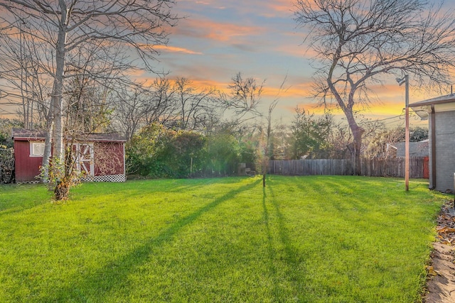 yard at dusk featuring a storage shed