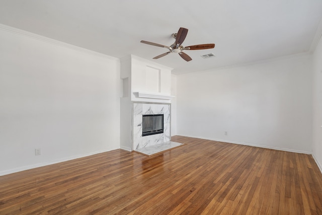 unfurnished living room with ceiling fan, wood-type flooring, crown molding, and a premium fireplace