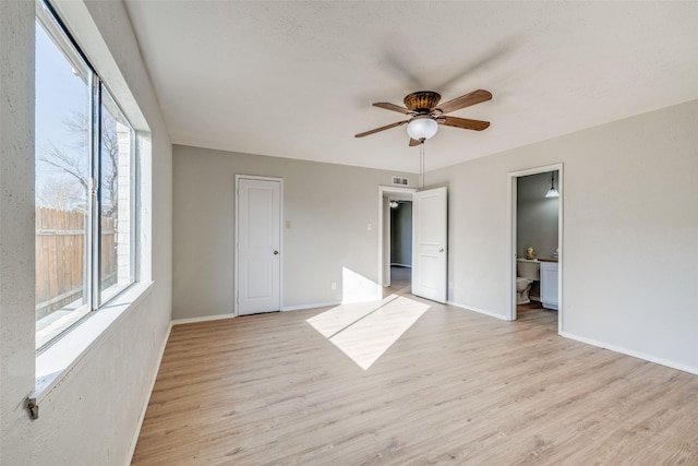 unfurnished bedroom featuring ceiling fan, light hardwood / wood-style floors, connected bathroom, and multiple windows