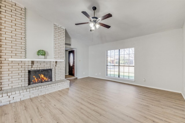 unfurnished living room featuring vaulted ceiling, a brick fireplace, light hardwood / wood-style floors, and ceiling fan