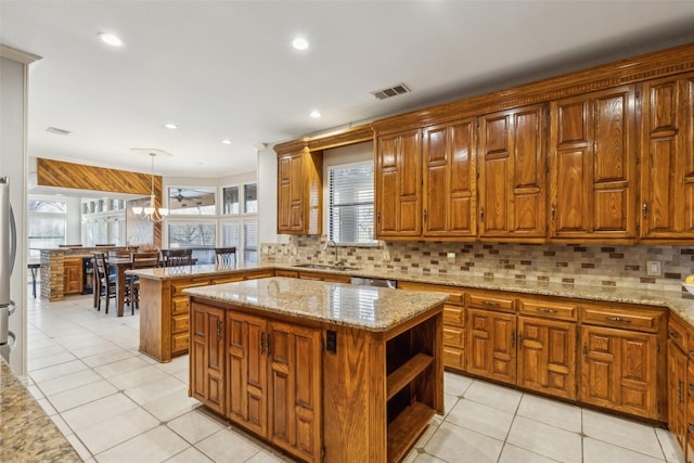 kitchen featuring light tile patterned floors, light stone countertops, pendant lighting, and a center island