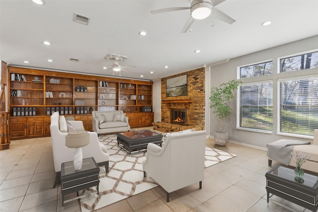 tiled living room featuring a brick fireplace, built in shelves, and ceiling fan