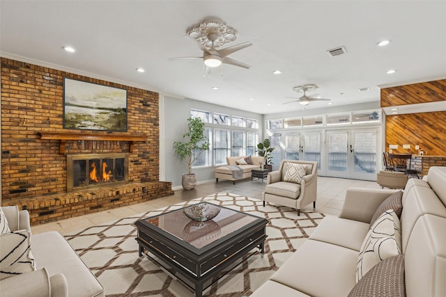 living room with ceiling fan, a fireplace, wooden walls, light tile patterned floors, and french doors