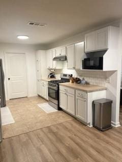 kitchen with tasteful backsplash, stainless steel stove, light hardwood / wood-style flooring, and white cabinets