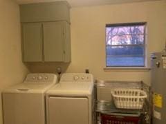 washroom with cabinets, washing machine and dryer, and water heater