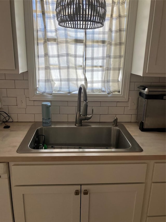 kitchen with white cabinetry, sink, backsplash, and white dishwasher