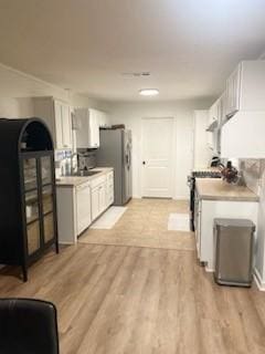 kitchen with white cabinetry, appliances with stainless steel finishes, and light hardwood / wood-style flooring