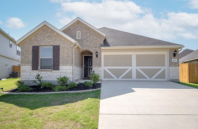 view of front of property featuring a front lawn, central air condition unit, and a garage