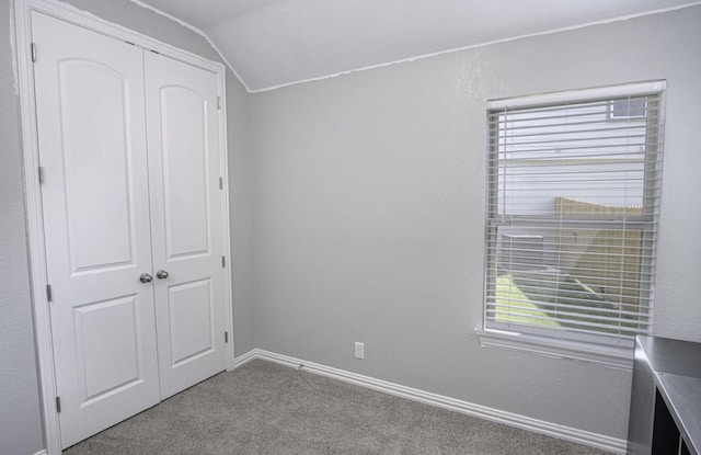 unfurnished bedroom featuring a closet, carpet flooring, and lofted ceiling