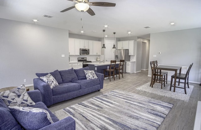 living room with ceiling fan, sink, and light hardwood / wood-style floors