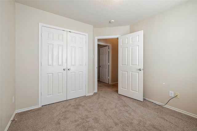 unfurnished bedroom with baseboards, a closet, and light colored carpet