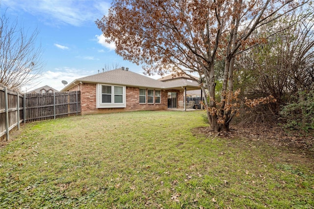 back of property with brick siding, a yard, and a fenced backyard