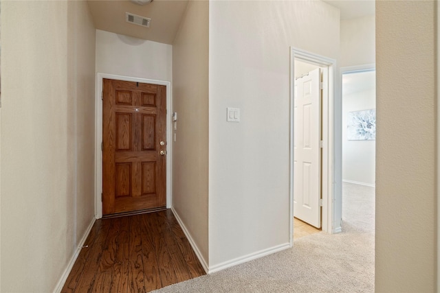 hall featuring light carpet, baseboards, and visible vents