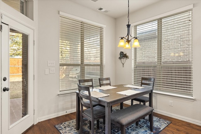 dining space with dark wood-type flooring, plenty of natural light, and a chandelier