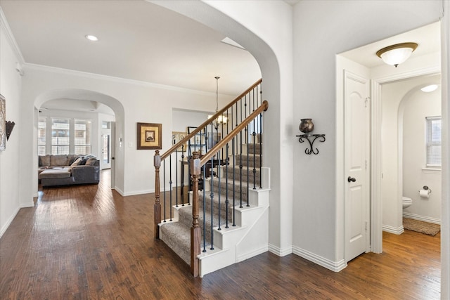 stairs featuring a notable chandelier, ornamental molding, and hardwood / wood-style flooring