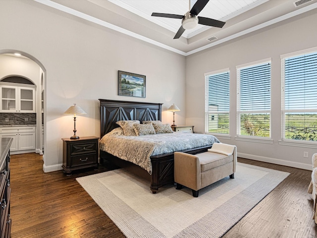 bedroom featuring ceiling fan, crown molding, dark hardwood / wood-style floors, and a raised ceiling