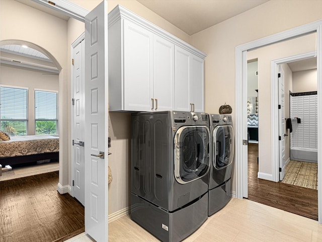 laundry room with cabinets, light hardwood / wood-style floors, and independent washer and dryer