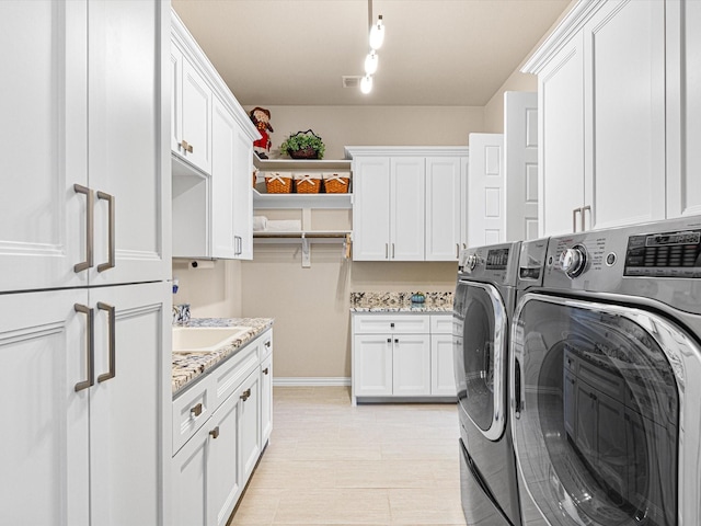 washroom with cabinets, sink, and washing machine and clothes dryer