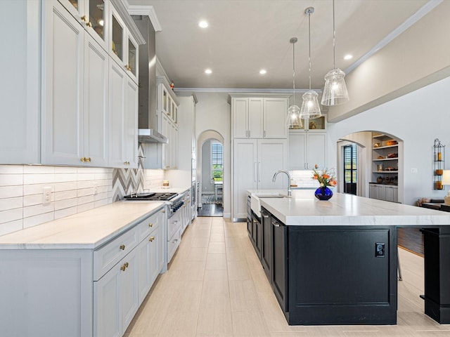 kitchen with a spacious island, decorative light fixtures, white cabinetry, backsplash, and high end stove