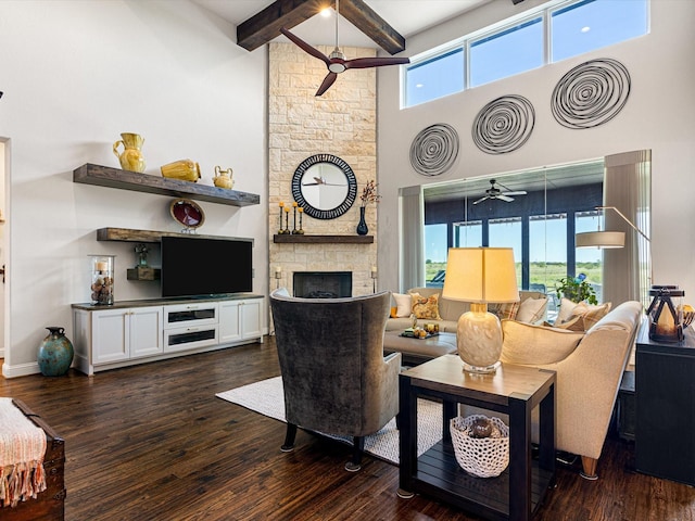 living room with a towering ceiling, dark hardwood / wood-style floors, beam ceiling, and a stone fireplace