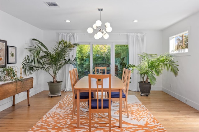 dining space featuring light wood-type flooring, a healthy amount of sunlight, and an inviting chandelier