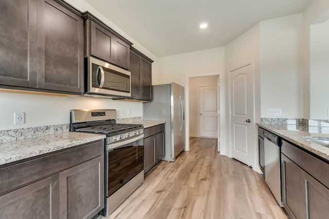 kitchen featuring light wood-type flooring, stainless steel appliances, dark brown cabinets, and light stone counters