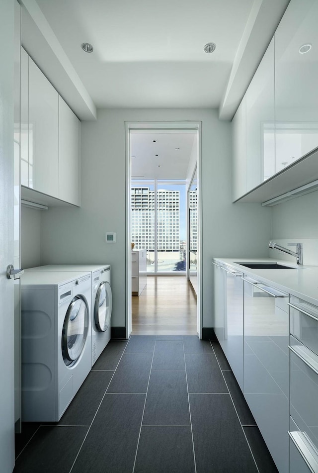 laundry area with dark tile patterned floors, sink, washer and dryer, and cabinets