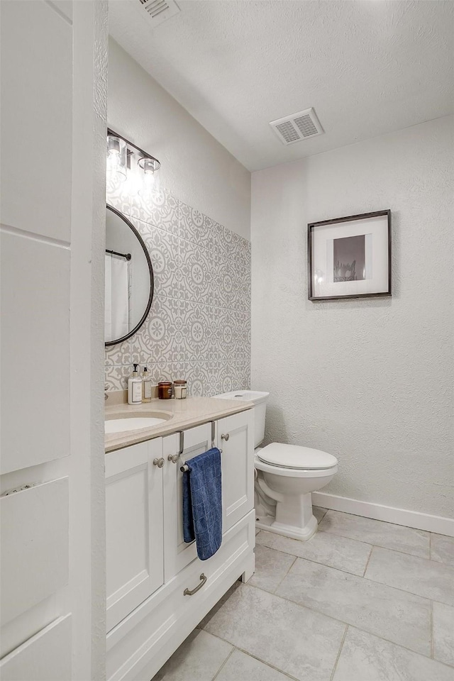 bathroom with toilet, vanity, and a textured ceiling