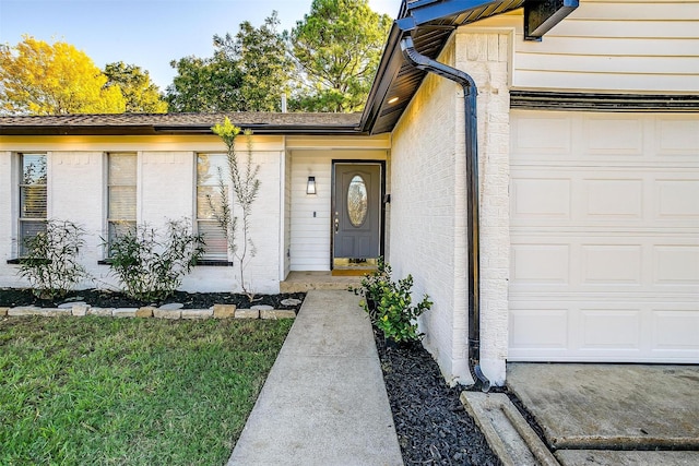 entrance to property with a garage and a yard