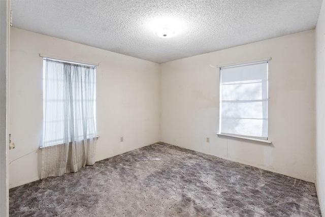 unfurnished room with a textured ceiling and carpet flooring