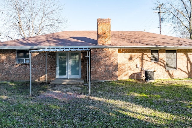 back of property with a lawn, french doors, and central air condition unit