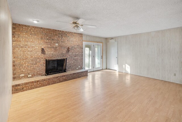 unfurnished living room featuring a textured ceiling, ceiling fan, and light wood-type flooring