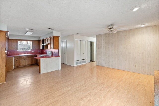 unfurnished living room featuring a textured ceiling, ceiling fan, a fireplace, and light wood-type flooring