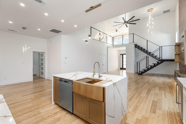 kitchen with light hardwood / wood-style floors, a large island, dishwasher, pendant lighting, and light stone counters